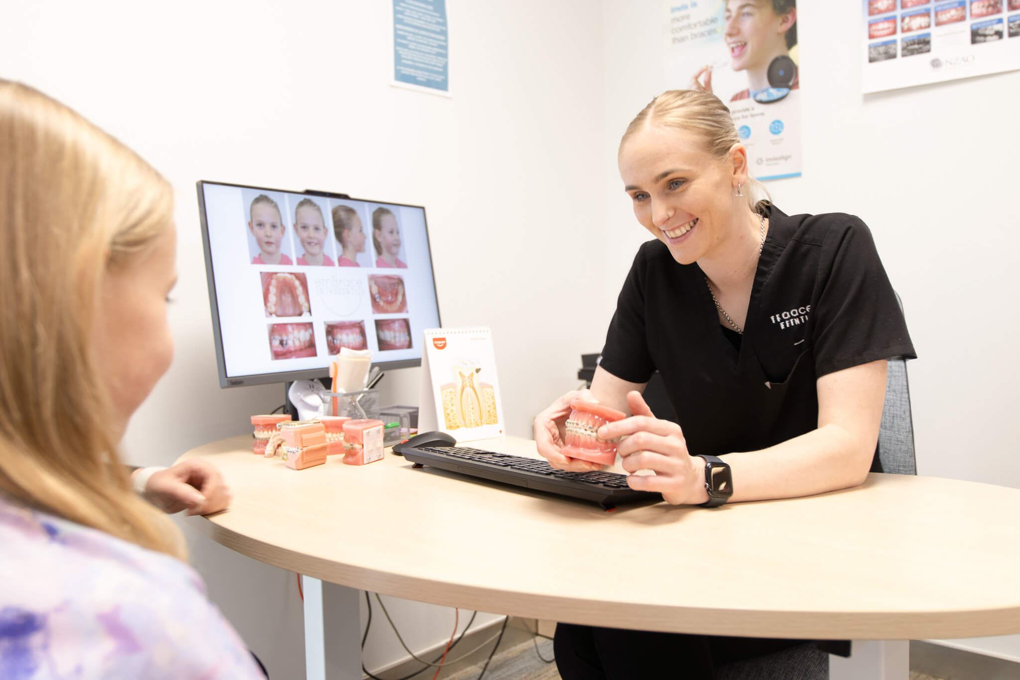 Orthodontist explaining braces treatment to child during consultation