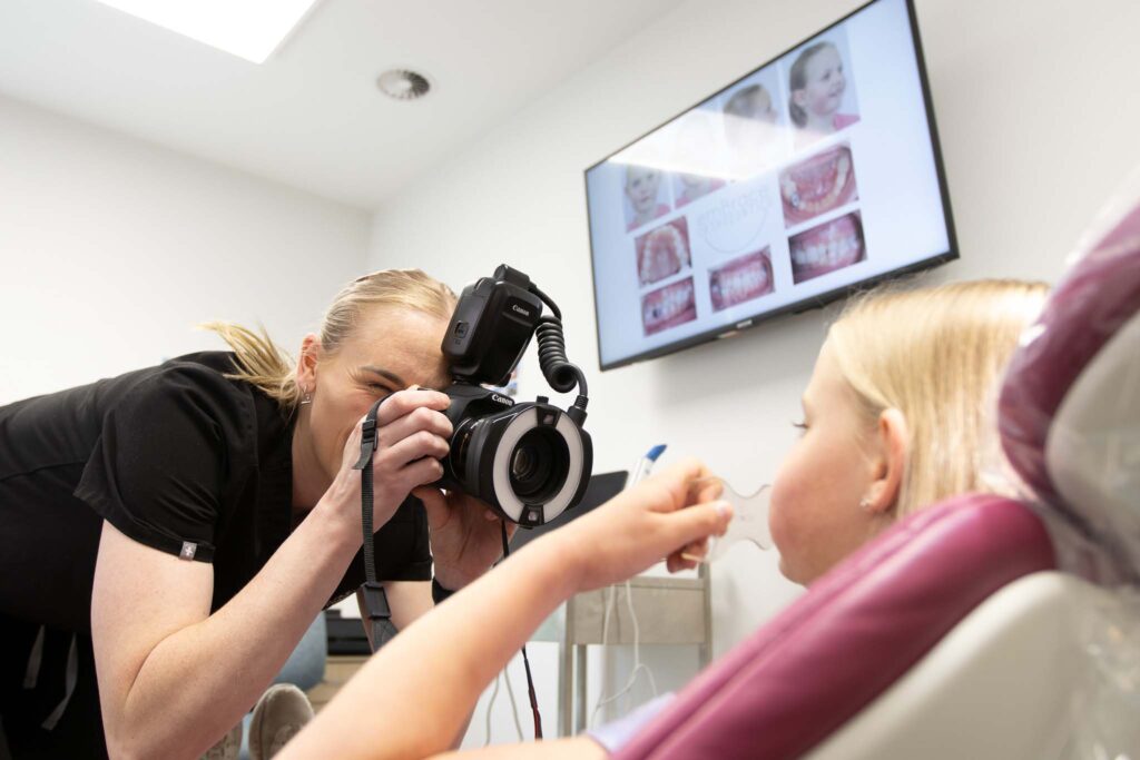 Orthodontist taking diagnostic photos during child’s orthodontic assessment